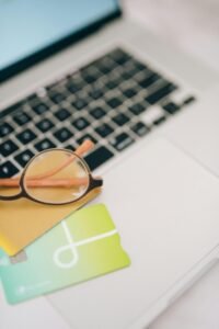 Close-up of eyeglasses and credit cards on a laptop, representing online shopping and digital finance.